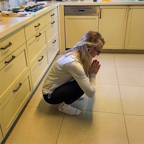 Lucia agachando na cozinha